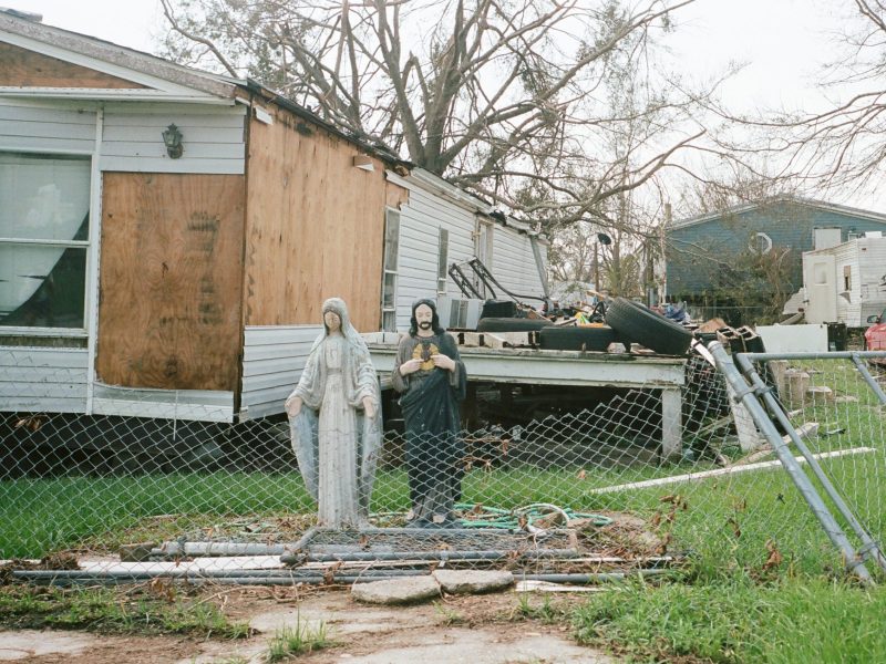 A statue of Mary and Jesus sits in front of a damaged mobile home in Ashland
