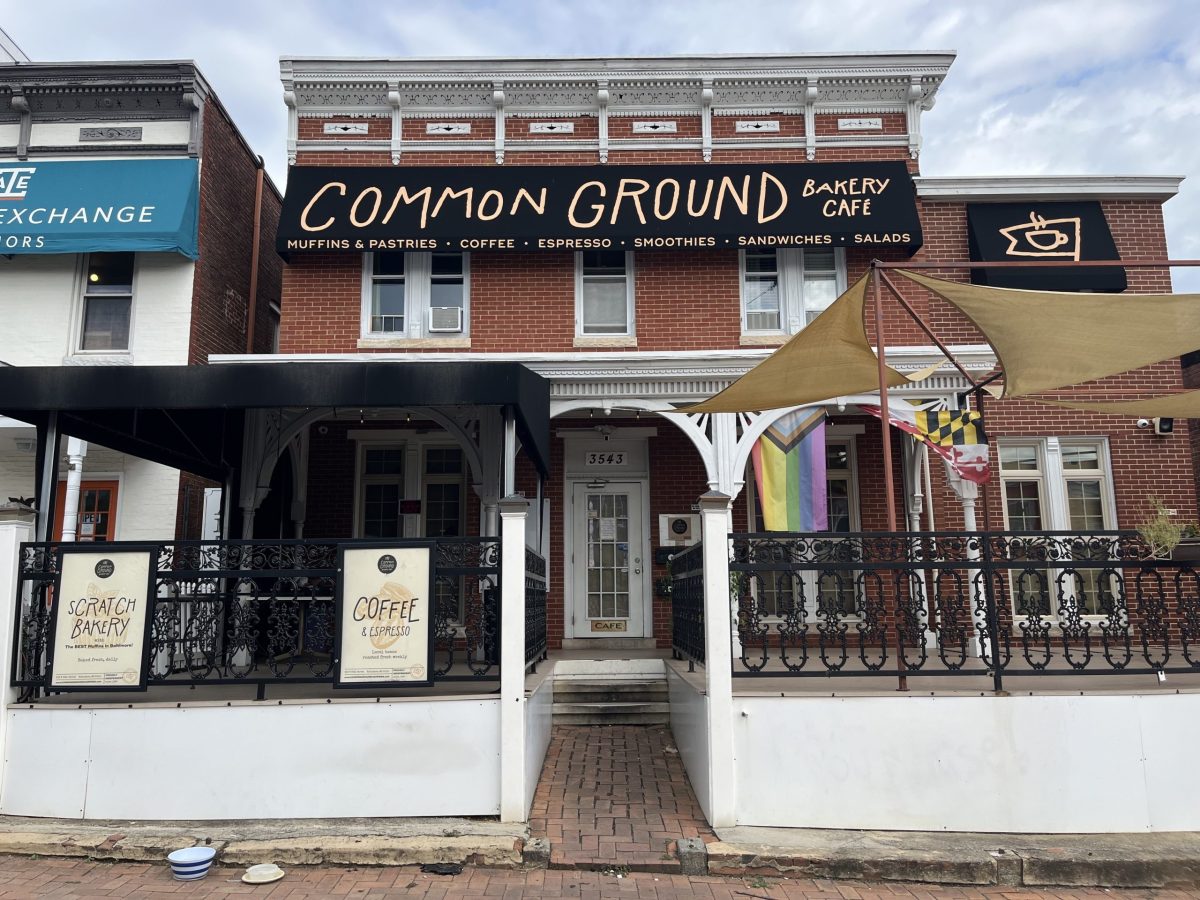 The exterior of a coffeeshhop—a two story brick building with an inviting porch-like patio, with a large sign that reads "Common Ground"