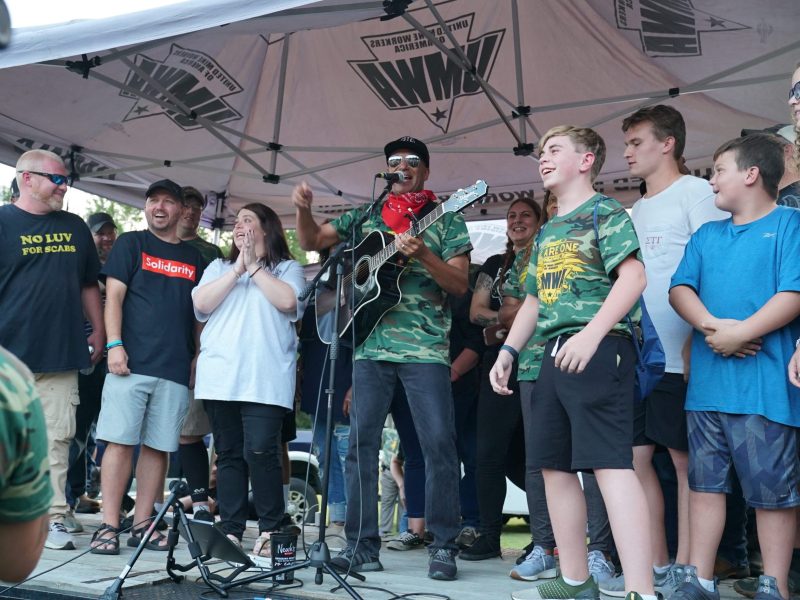 Tom Morello stands on stage with striking Warrior Met Coal miners and their families during a solidarity rally held by the United Mine Workers of America (UMWA) in Brookwood, Alabama, on Sept. 14, 2022.