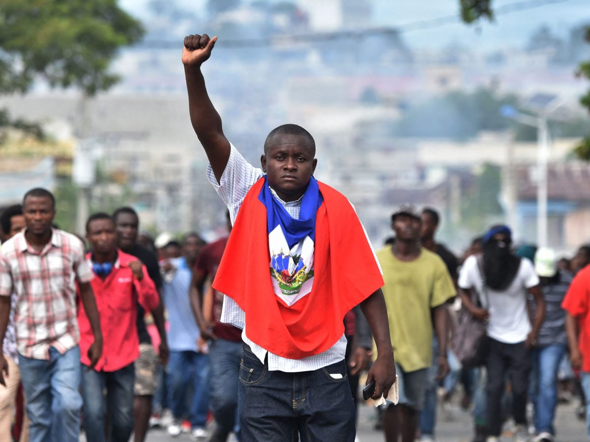 A man holds up his fist as demonstrators march through the streets of Port-au-Prince, on November 23, 2018, demanding the resignation of Haitian President Jovenel Moise. Photo by HECTOR RETAMAL/AFP via Getty Images