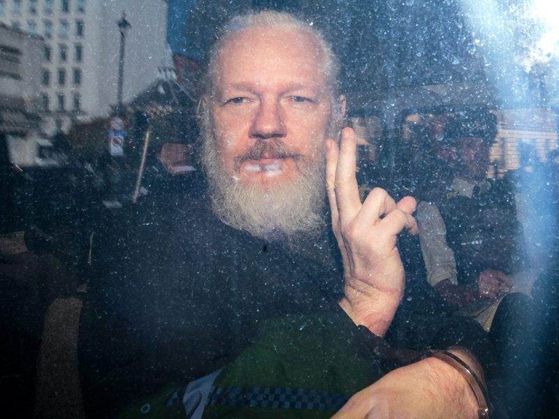 Julian Assange gestures to the media from a police vehicle on his arrival at Westminster Magistrates court on April 11, 2019, in London, England.
