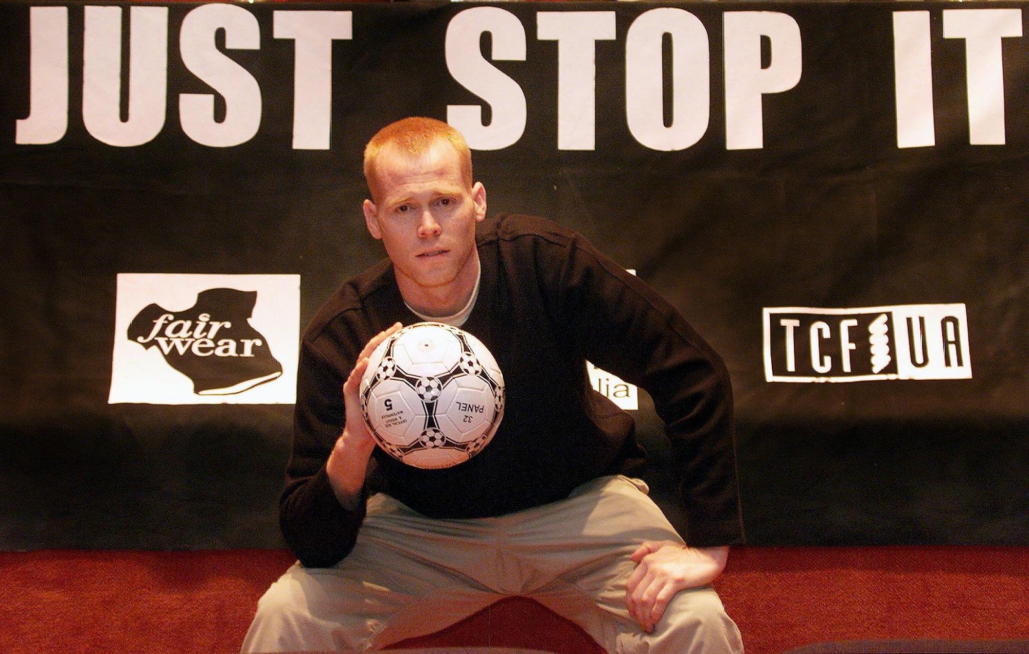 Former American soccer pro Jim Keady sits in front of a sign playing on footwear giant Nike's 'Just Do It' slogan after Keady spent a month living in Indonesia trying to live on the wage of a Nike worker. Sydney, Sept. 4, 2000. Photo by WILLIAM WEST/AFP via Getty Images