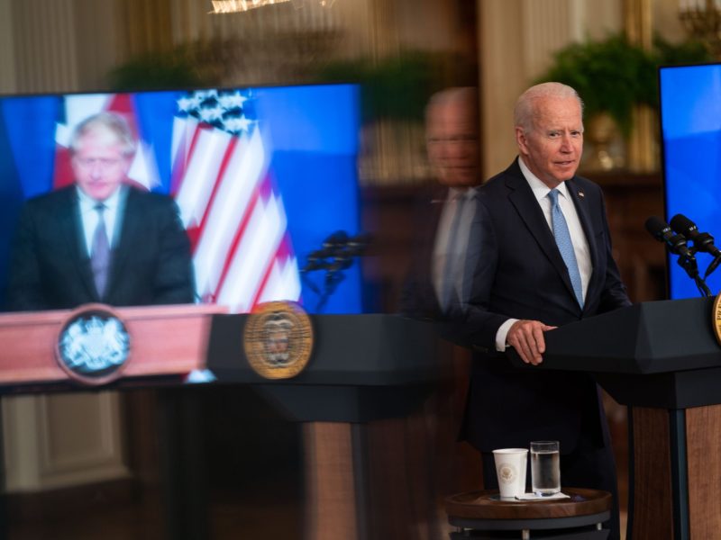 UK Prime Minister Boris Johnson appears on screen to the left of President Joe Biden as he delivers remarks about national seurity initiative