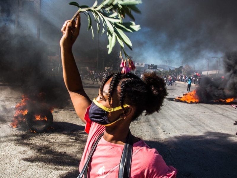 A woman holds a leafy twig as part of a protest for better working conditions for garment workers in Haiti