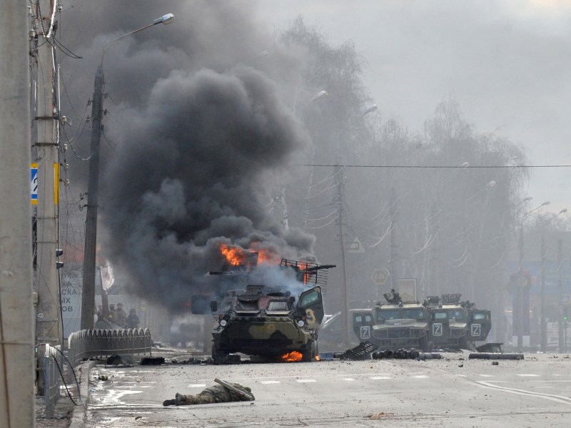 An unidentified soldier's body lies near a burning Russian Armoured personnel carrier (APC) during fighting with the Ukrainian armed forces in Kharkiv, on Feb. 27, 2022.