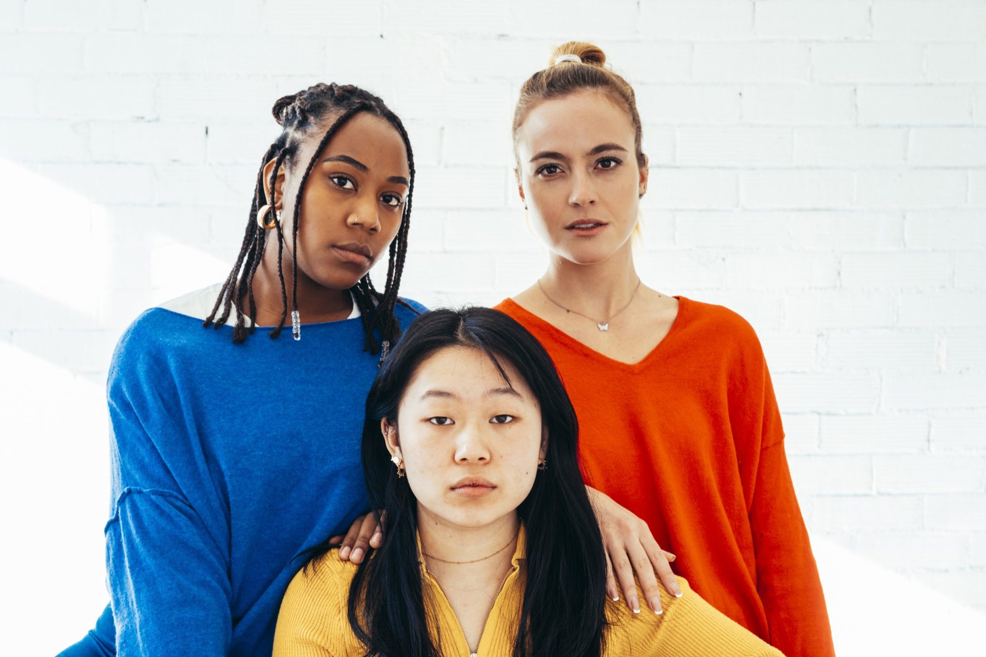 Group of multi-ethnic women looking at the camera with serious face while sitting together. Feminism and equality concept.