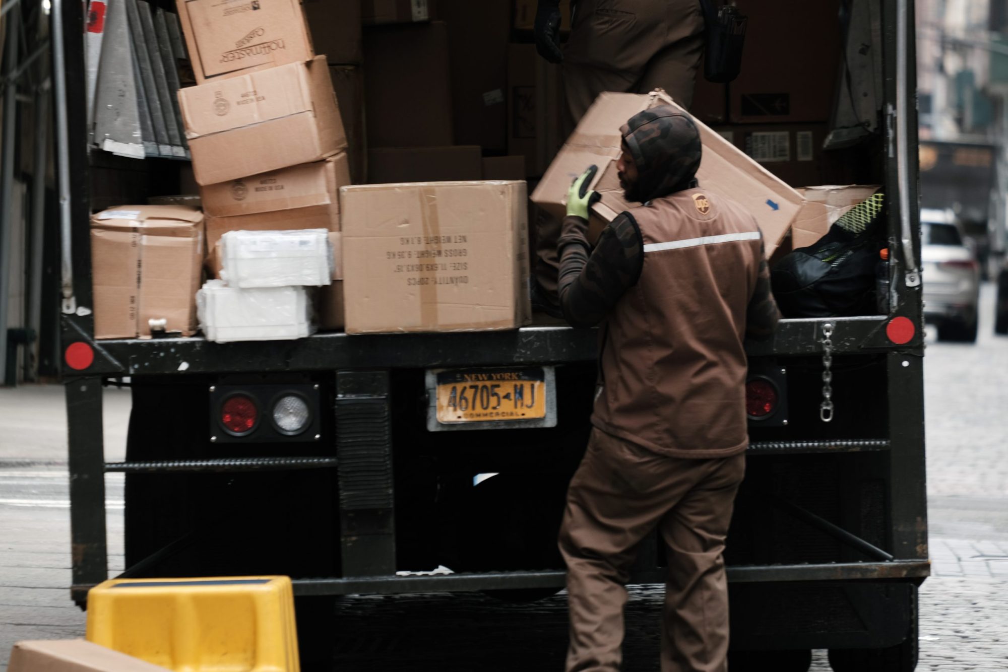 A UPS delivery driver unloads packages out of the back of a delivery truck.