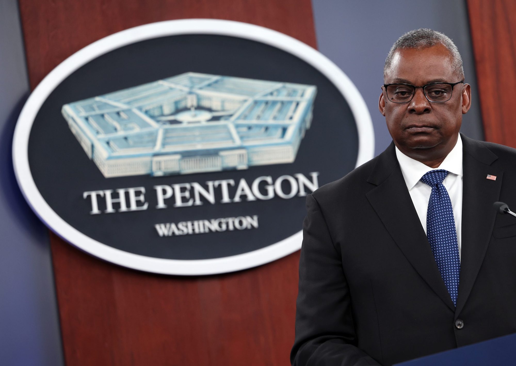 Man in a suit stands in front of a sign that reads THE PENTAGON