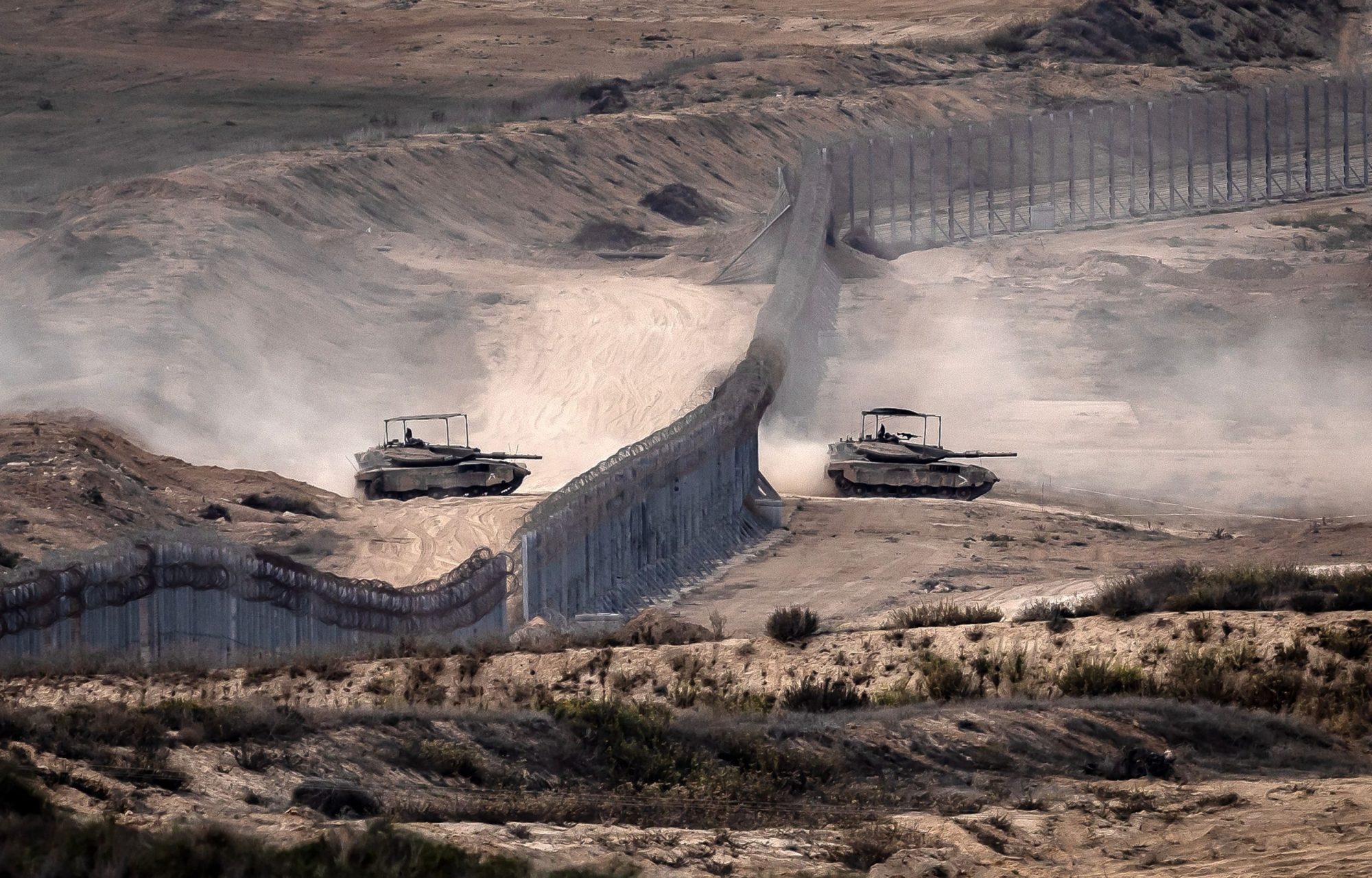 Israeli tanks cross a barbed wire fence at a position along the border with the Gaza Strip and southern Israel on November 12, 2023, amid ongoing battles between Israel and the Palestinian militant group Hamas. Photo by FADEL SENNA/AFP via Getty Images