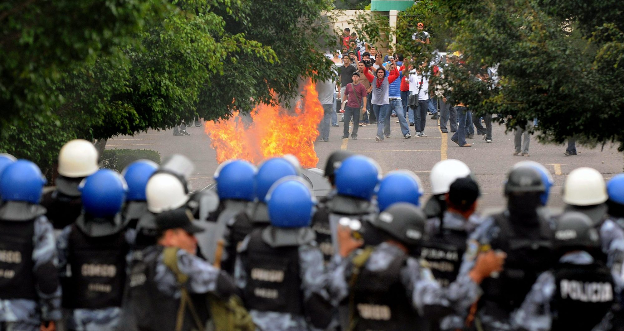 Honduran riot policemen form a barrier during clshes with students from the Universidad Nacional Autonoma de Honduras (UNAH), who demand the restitution of ousted President Manuel Zelaya, on August 5, 2009 in Tegucigalpa. Photo by ORLANDO SIERRA/AFP via Getty Images