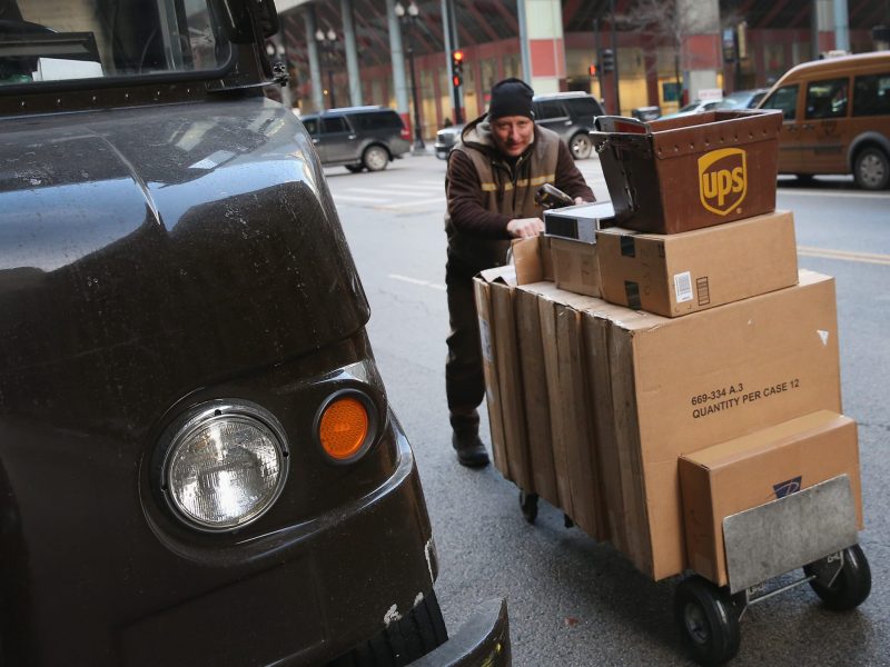 A UPS worker on a winter's day pushing a cart full of packages.
