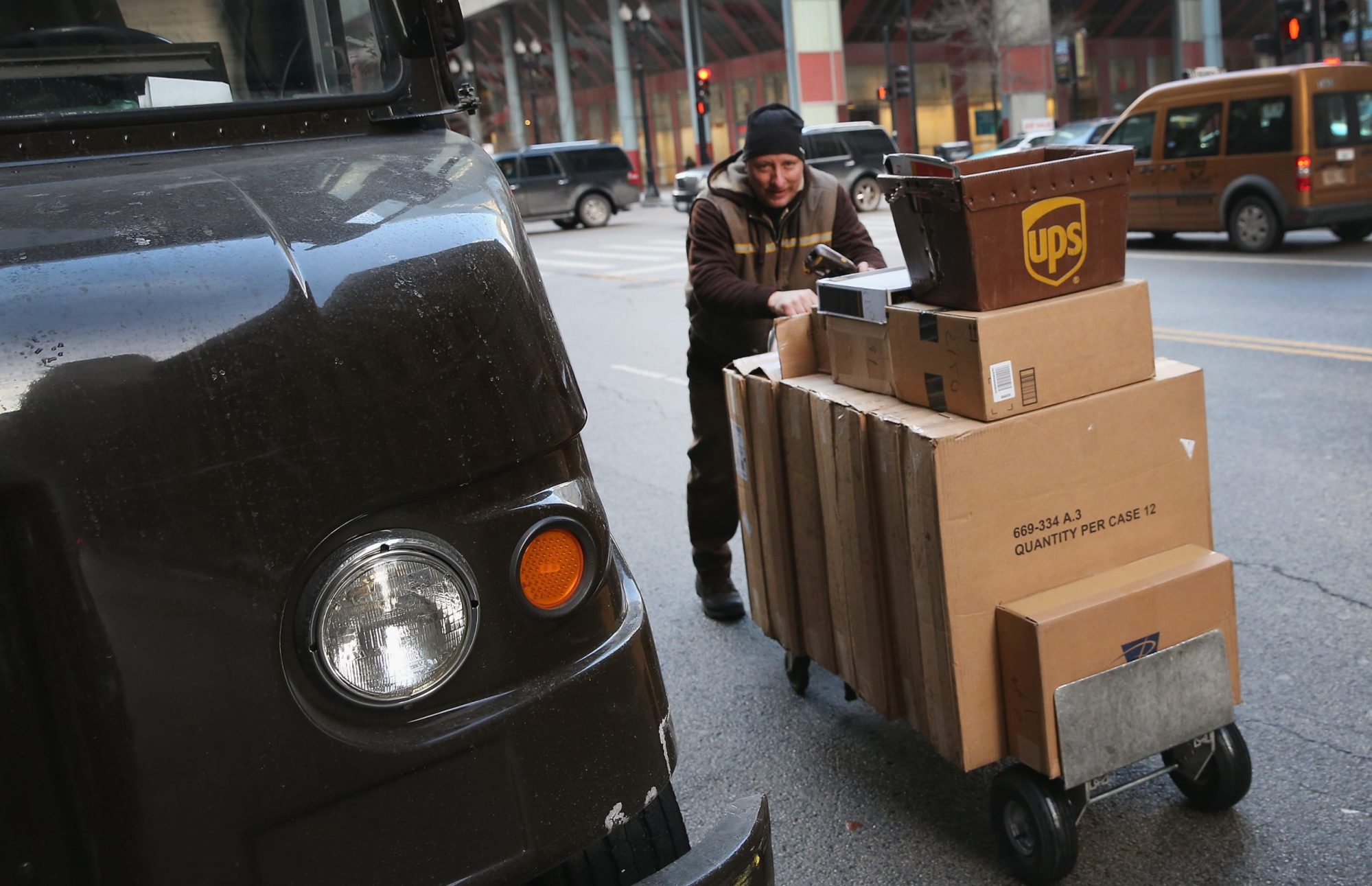 A UPS worker on a winter's day pushing a cart full of packages.