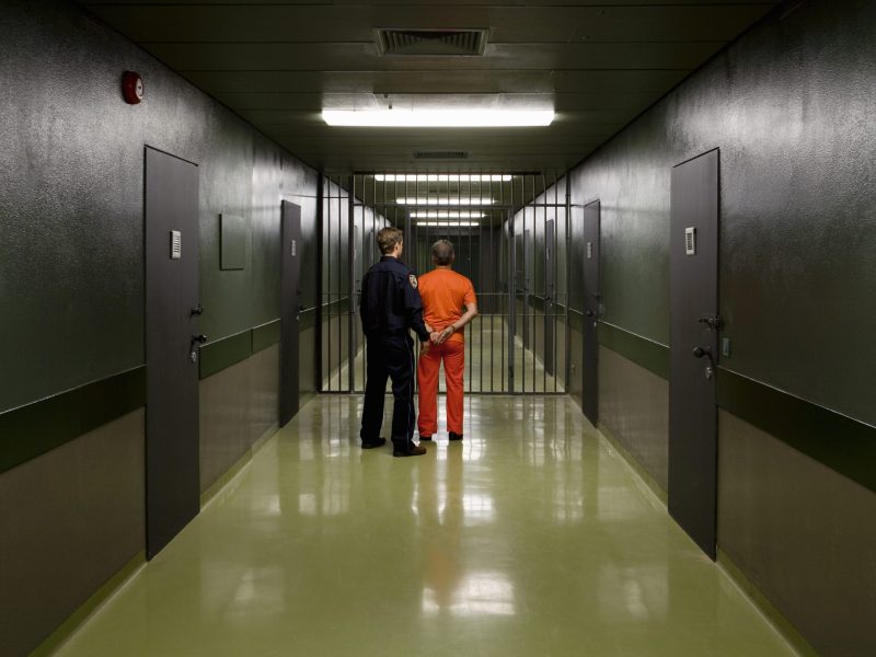 A prison guard leading a prisoner along a corridor