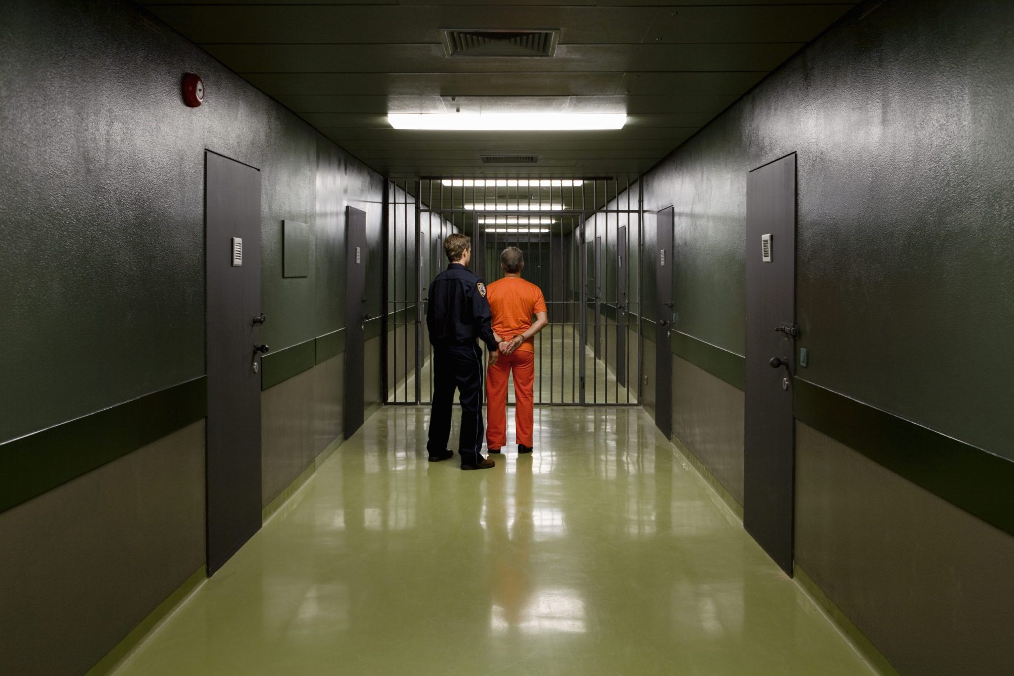 A prison guard leading a prisoner along a corridor