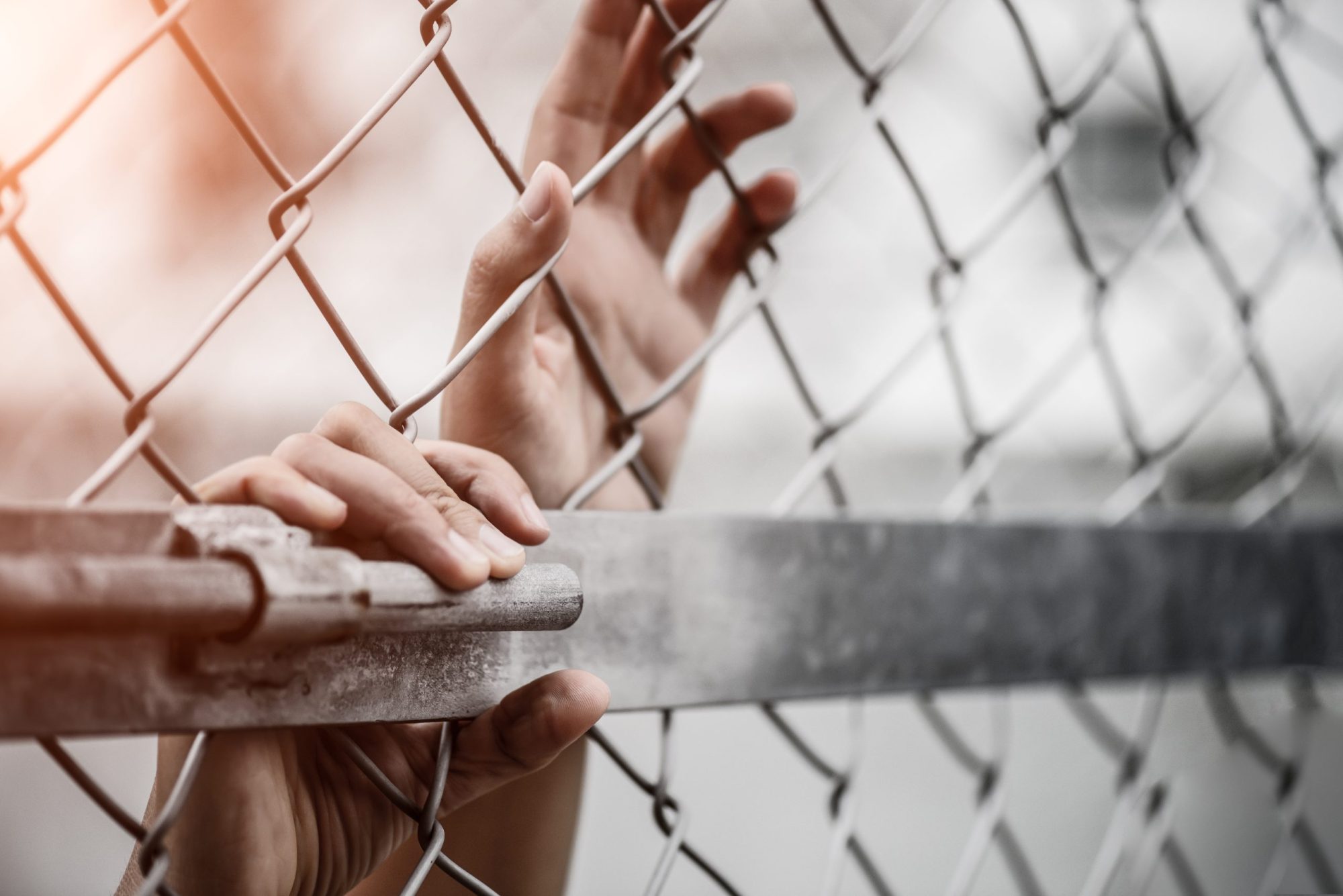Woman hand holding on chain link fence for remember Human Rights Day. Via Getty Images