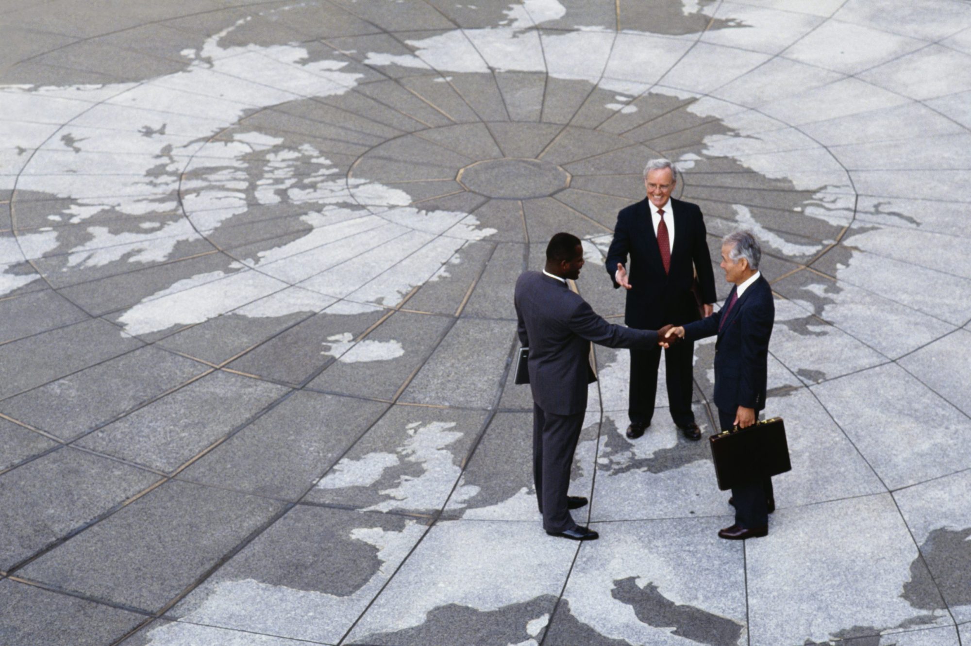 Businessmen shaking hands on map of globe