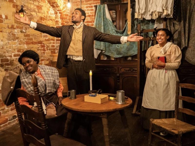 April Louise as Christine Williams (left), KC Simms as Isaac Richardson (center), and Alexandra Miles as Annette Williams (right), in the Jacona family's bar and grocery, the main place of gathering in the immersive play "The Family Line," which is set during an 1892 general strike in New Orleans. Photo by Joshua Brasted.