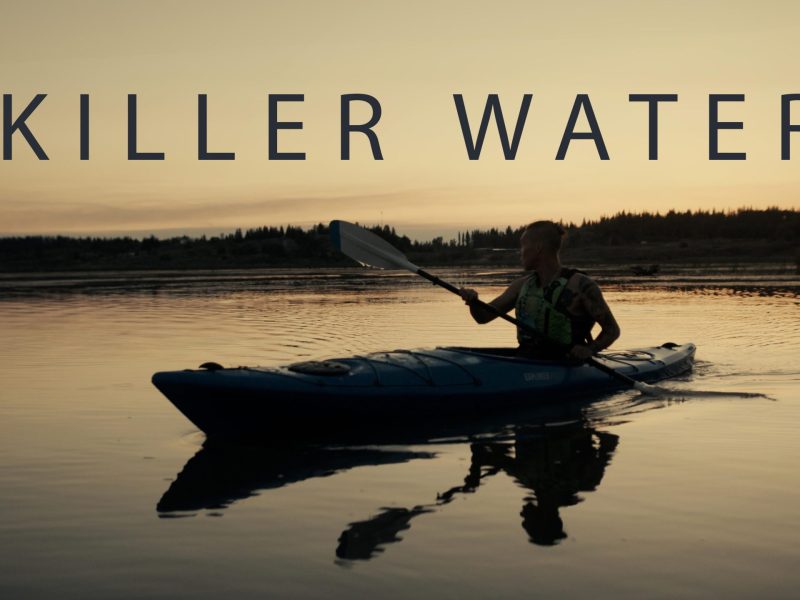 Movie poster for "Killer Water" featuring a photo of Mikisew Cree member Calvin Waquan paddling on a kayak near Lake Athabasca at dusk with the words "Killer Water" above him. Poster/image by Geordie Day.