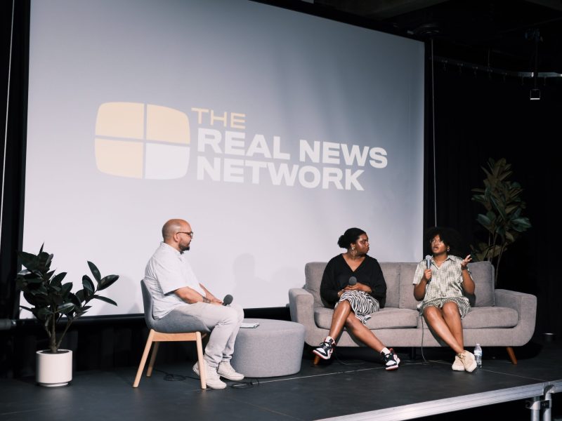 TRNN Editor-in-Chief Maximillian Alvarez (left) sits across from POWER Fellows Tinashe Chingarande (middle) and Ahmari Anthony (right) on the main stage at the TRNN studio in Baltimore, Maryland, during the Baltimore POWER: Emerging Journalist Showcase event on Sept. 7, 2023, cohosted by TRNN and Just Media. Photo by TRNN.