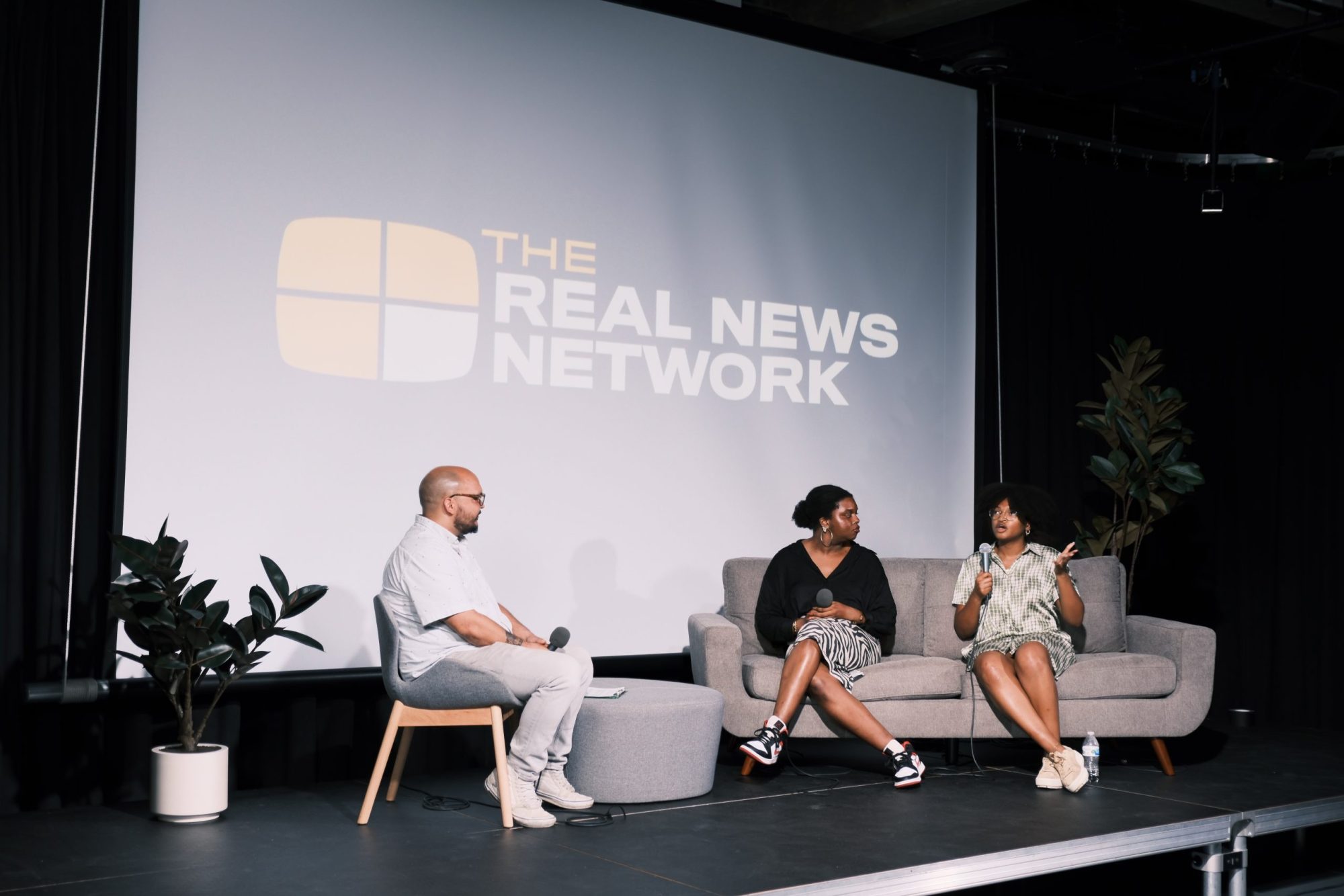 TRNN Editor-in-Chief Maximillian Alvarez (left) sits across from POWER Fellows Tinashe Chingarande (middle) and Ahmari Anthony (right) on the main stage at the TRNN studio in Baltimore, Maryland, during the Baltimore POWER: Emerging Journalist Showcase event on Sept. 7, 2023, cohosted by TRNN and Just Media. Photo by TRNN.