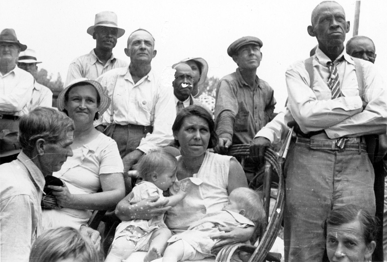 Men, women, and children, black and white, listen to a speaker at an outdoor Southern Tenant Farmers Union meeting, 1937. Wikimedia Commons