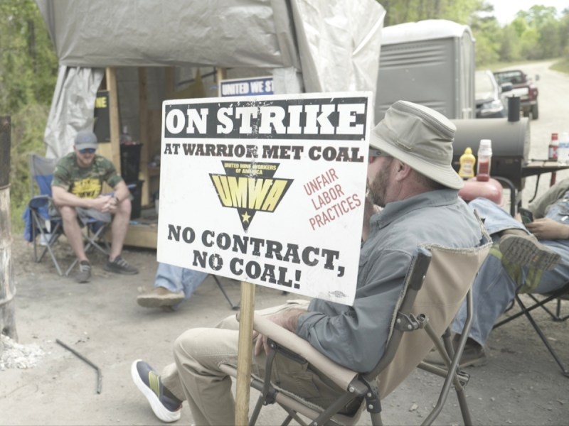 Striking coal miners sit on a picket line