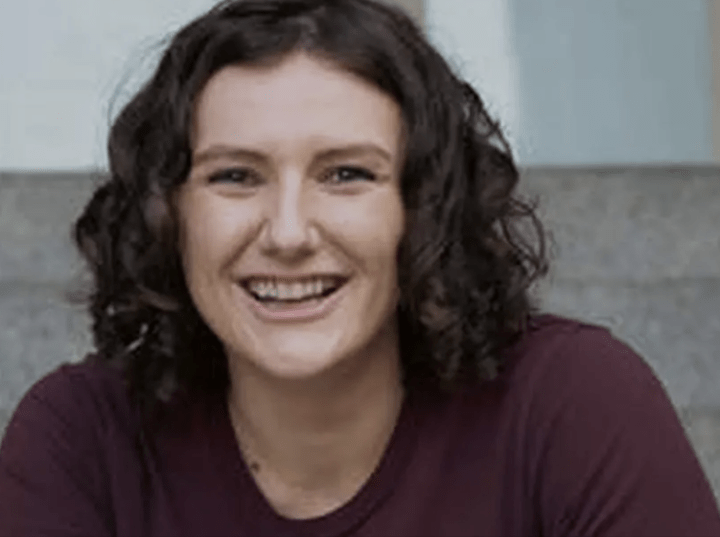 Close-up portrait of LaPere smiling. She is wearing a maroon t-shirt and has loose, brown curls.