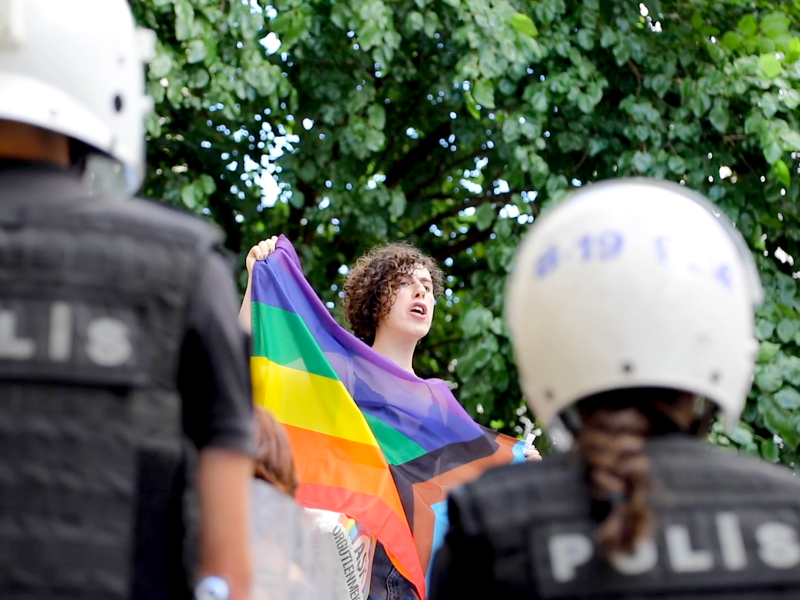 A Pride demonstrator holds up a rainbow flag in front of two Turkish police officers in Istanbul, Turkey, on June 26, 2022.